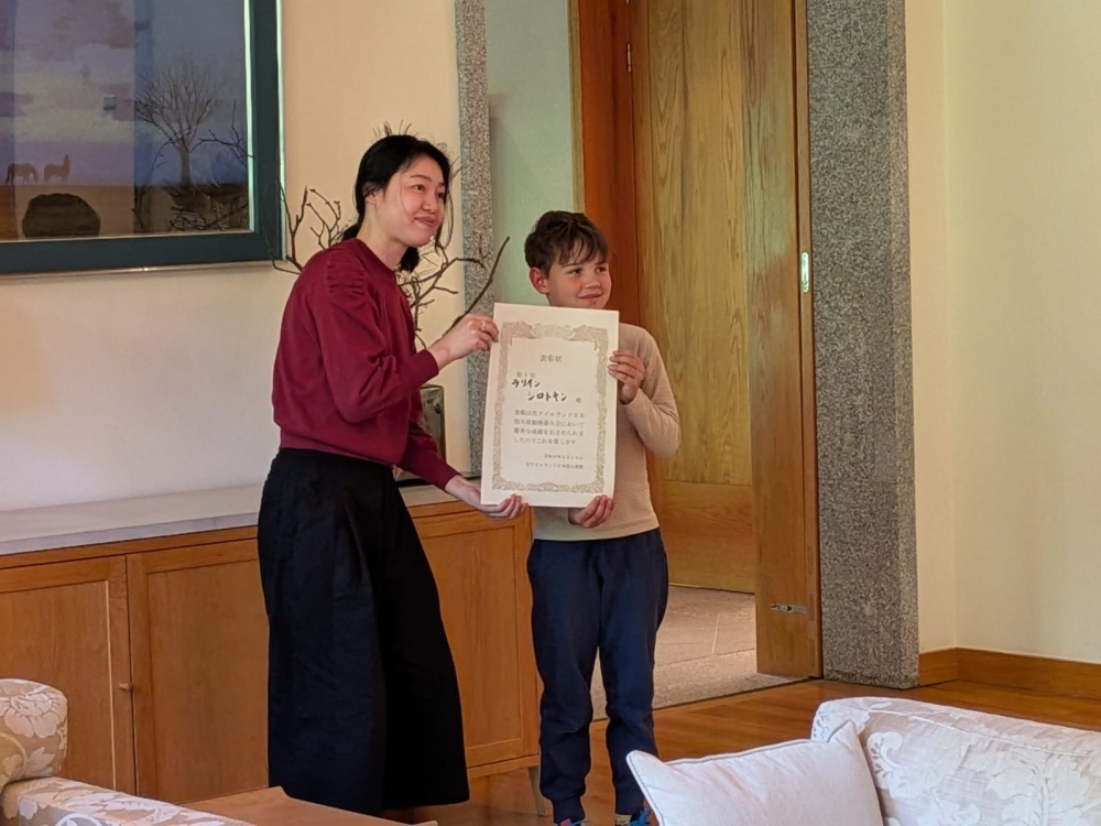 Mr Larion Syrotkin, holding his first-place certificate with an Embassy staff member.